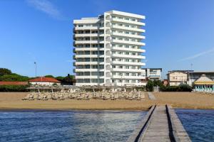 ein Hotel am Strand mit Stühlen und einem Gebäude in der Unterkunft Adriatic Palace Hotel in Lido di Jesolo