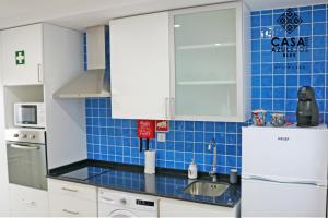 a blue tiled kitchen with a sink and a refrigerator at Casa do AZULejo - Blue in Peniche