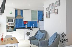 a kitchen with a washing machine and two chairs at Casa do AZULejo - Blue in Peniche