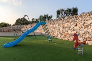 un parque infantil con 2 columpios y un tobogán en Trulli Beltramonto en Locorotondo