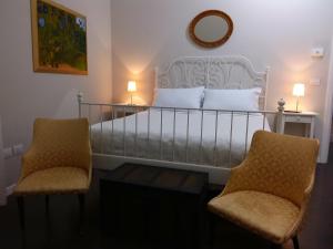a bedroom with a bed with two chairs and a mirror at Dimora del Castellano in Gioia del Colle