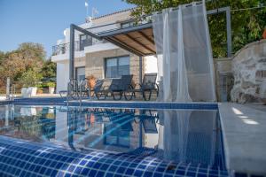 a swimming pool with chairs next to a house at Villa Infinite Blu in Paphos