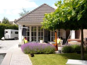 a small house with purple flowers in the yard at Gardenhouse with private jacuzzi and sauna in Teteringen