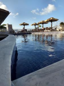 - une piscine avec des tables et des parasols sur la plage dans l'établissement Pipa's Bay Apartamentos, à Pipa