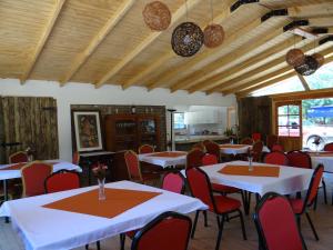 une salle à manger avec des tables blanches et des chaises rouges dans l'établissement Viña Don Heraldo, à De Cauquenes