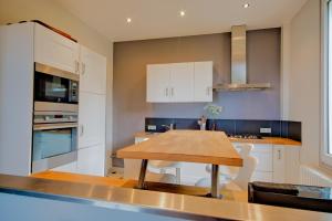 a kitchen with white cabinets and a wooden table at Villa Classée 4 étoiles Vue mer exceptionnelle in Trouville-sur-Mer