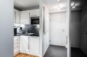 een keuken met witte kasten en een deur naar een kamer bij 2ndhomes Luxury Kamppi Center Apartment with Sauna and Terrace in Helsinki