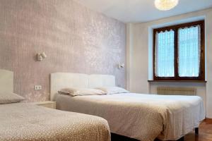 モルヴェーノにあるAppartamento Zeni - Dolomiti di Brentaのベッドルーム1室(ベッド2台、窓付)