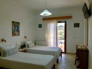 a hotel room with two beds and a window at Floros Apartments in Agios Stefanos