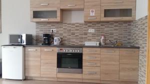 cocina con armarios de madera y nevera blanca en Váralja Apartman en Tata