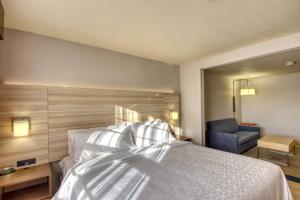 um quarto com uma cama e uma cadeira em Holiday Inn Express Hotel & Suites Milwaukee Airport, an IHG Hotel em Milwaukee