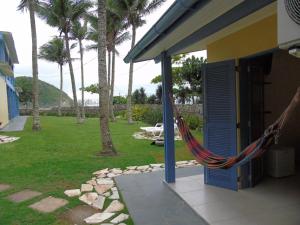 een hangmat buiten een huis met palmbomen bij Pousada Sobre as Pedras in Itanhaém