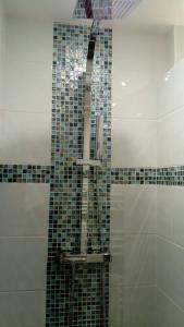 a bathroom with a shower with a tiled wall at The Originals City, Hôtel Novella, Nantes Centre Gare in Nantes