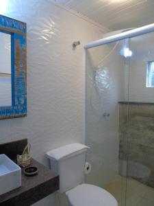 a bathroom with a toilet and a glass shower at Pousada Sobre as Pedras in Itanhaém