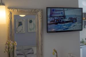 ein Spiegel hängt an einer Wand mit einem Bild drauf in der Unterkunft Cyclades Studios in Parikia