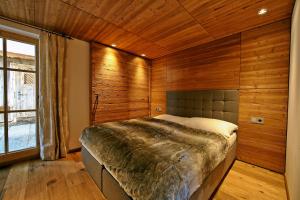 a bedroom with a bed with a wooden wall at Villa Alpin in Kaltenbach