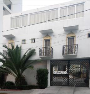 un edificio blanco con balcones y una palmera en Casa Shalom Puebla, en Puebla