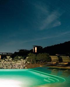 a swimming pool at night with a building in the background at Encuentro Guadalupe in Valle de Guadalupe