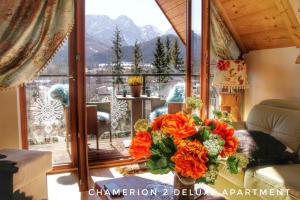 een vaas met oranje bloemen op een tafel voor een raam bij Polana Szymoszkowa Ski Resort - Chamerion Apartments in Zakopane
