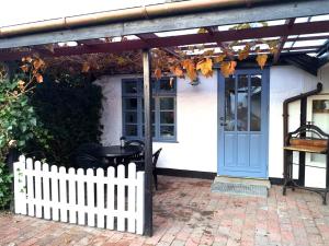 una casa bianca con una porta blu e una recinzione di Cosy cottage in a garden a Ishøj