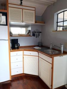 a kitchen with white cabinets and a sink at Cosy cottage in a garden in Ishøj