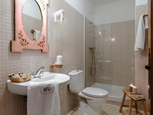 Un baño con lavabo, inodoro y espejo. en Hospedería del Valle Boutique Apartments, en Gargantilla del Lozoya 37 fotos más
