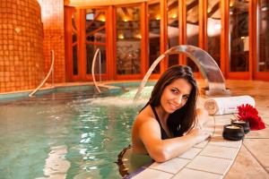 a woman laying in a swimming pool at Hotel Piroska in Bük