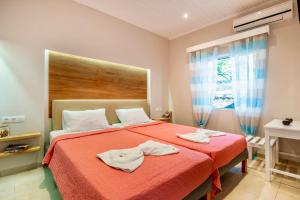 a bedroom with a red bed with two towels on it at Nissaki Suite Kalypso by Sealand Villas in Nisakion
