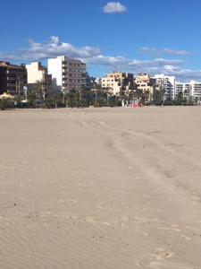 a sandy beach with a city in the background at Un impresionante apartamento cerca de la playa/An impressive apartment near the beach. in Puerto de Sagunto