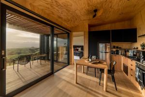 eine Küche und ein Esszimmer mit einem Tisch und einem Balkon in der Unterkunft Whitimanuka Retreat in Martinborough 