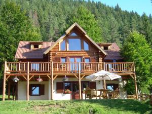a log cabin with a deck and a table at Veresko Villa in Lacu Rosu