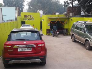 two cars parked in a parking lot in front of a hotel at Hotel Blue Heaven in Fatehpur Sīkri