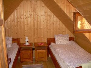 two beds in a small room with wooden walls at Veresko Villa in Lacu Rosu