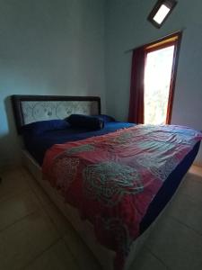 ein Schlafzimmer mit einem Bett mit einer roten Decke und einem Fenster in der Unterkunft Red Beach Homestay in Pasanggaran