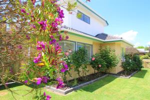 a house with purple flowers in the yard at AristaAir- Central City Townhouse in Rotorua