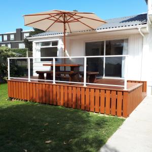 a deck with an umbrella and a picnic table at Guest house on Plummers Point in Tauranga