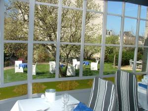 einen Tisch mit Stühlen und Blick auf den Garten durch ein Fenster in der Unterkunft Logis Hotel L'europe in Pontivy