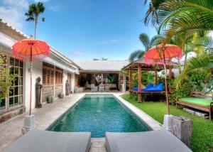 a pool in the backyard of a house with umbrellas at Coco Poco Villa Seminyak in Seminyak