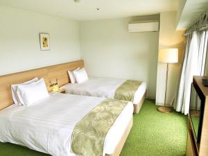 um quarto de hotel com duas camas e uma televisão em Hotel Heritage em Kumagaya
