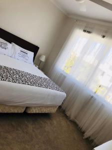 a bedroom with a white bedspread and white curtains at White Shells Luxury Apartments in Marcoola