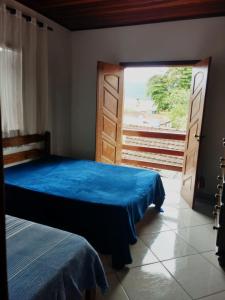 ein Schlafzimmer mit einem blauen Bett und einer Glasschiebetür in der Unterkunft Casa no Centro in Paraty