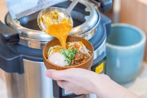 Vessel Hotel Higashi Hiroshima في هيغاشيهيروشيما: شخص يحمل وعاء من الطعام بملعقة