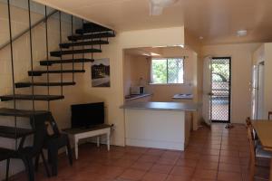 a living room with a spiral staircase and a kitchen at Pippies Beachhouse Backpackers in Rainbow Beach