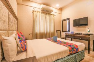 a hotel room with a bed and a desk at FabHotel Frazer Suites Pulikeshi Nagar in Bangalore