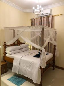 - une chambre dotée d'un lit à baldaquin avec des draps et des oreillers blancs dans l'établissement Bottoms Up, à Zanzibar City