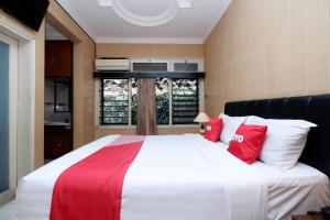 a bedroom with a large bed with red and white pillows at OYO 1843 Cahya Nirwana in Purwokerto