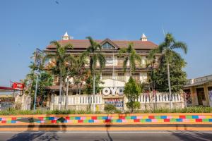 a large building with palm trees in front of it at Super OYO 1803 Hotel Sarangan Permai in Madiun