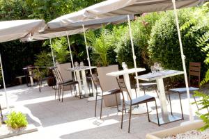 un groupe de tables et de chaises sous un parapluie dans l'établissement Kyriad Direct Marseille Est La Valentine, à La Penne-sur-Huveaune