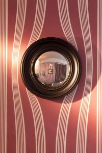 a round mirror on a red and white striped wall at Georgette Hôtel & Restaurant in Paris