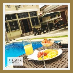 una mesa con un plato de comida y un vaso de zumo de naranja en Urdesa Suites Hotel, en Guayaquil